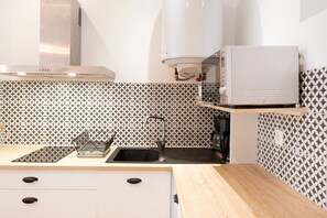 Una cocina moderna con microondas integrado, un lavamanos y un salpicadero decorativo.