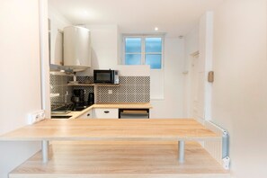 Una cocina compacta con encimera de madera, microondas y cafetera.