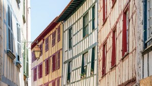 Una calle estrecha con edificios tradicionales de entramado de madera, cada uno con múltiples ventanas y contraventanas.