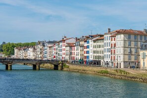 Un río con un puente de piedra, edificios coloridos de diversos estilos arquitectónicos y un cielo despejado.