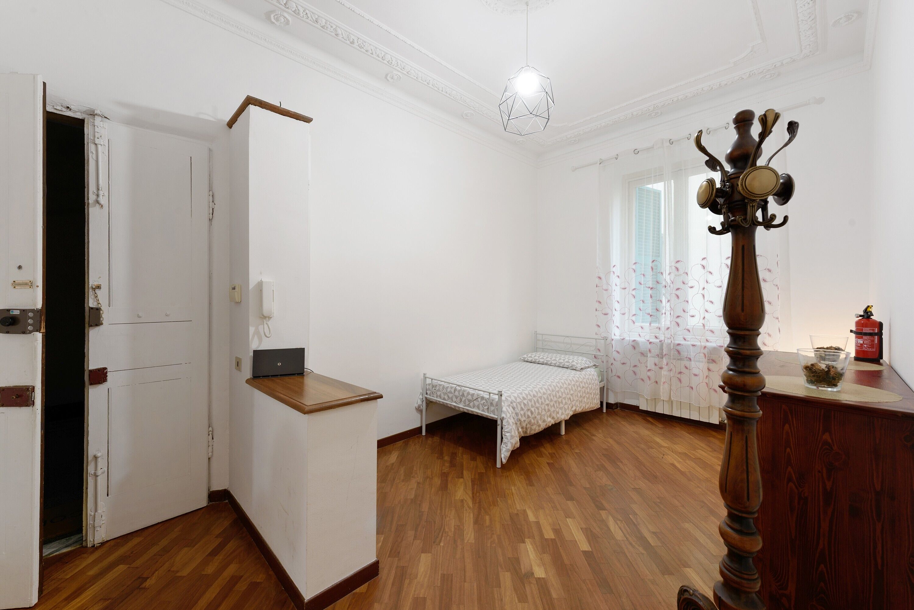 Une chambre comprenant un lit, un bureau, une armoire et un porte-manteau.