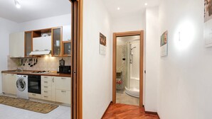 A compact kitchen with a washing machine, oven, and wooden cabinets.
