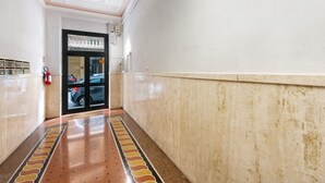 Un pasillo con piso estampado, un extintor y una puerta que da a un estacionamiento.