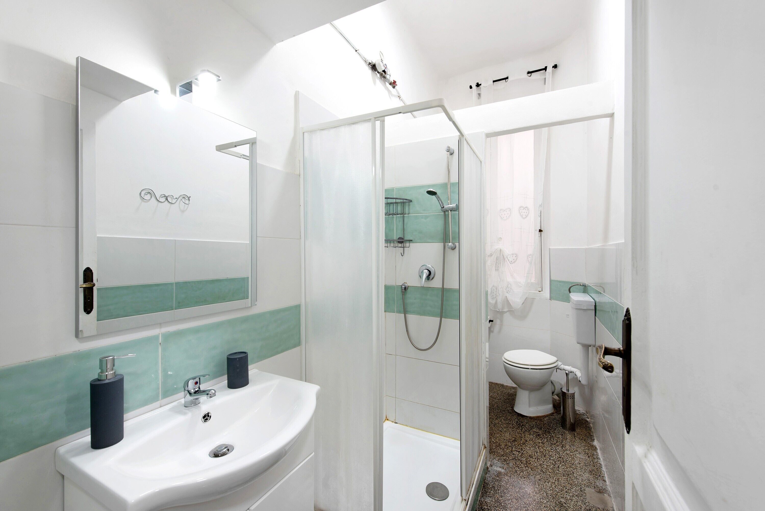 A bathroom with a white sink, a glass shower enclosure, and a toilet.