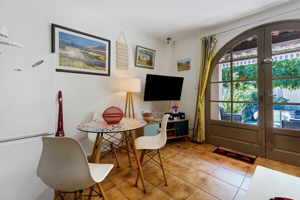 A small dining area with a table and chairs, a television, and artwork on the walls.