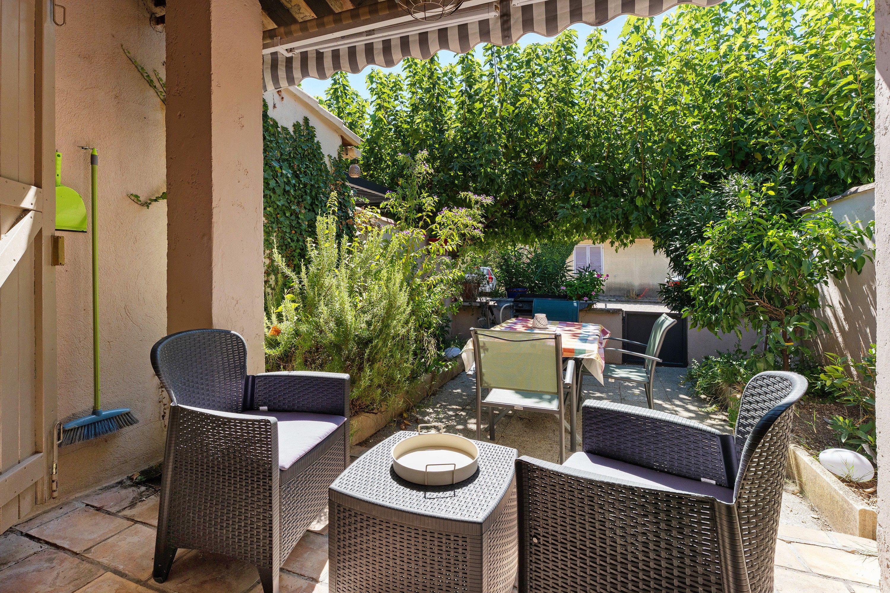 Un'area patio all'aperto con mobili in vimini, un tavolo e un barbecue.