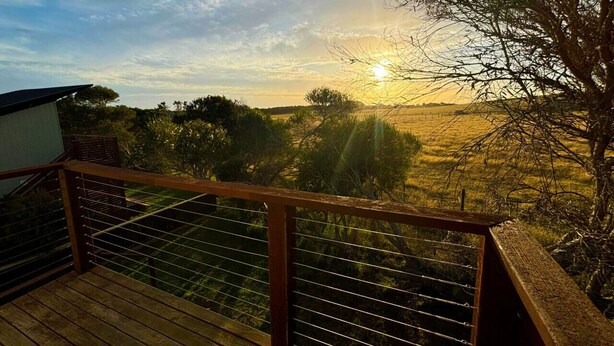 A balcony with a view of a sunset over a field.