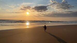 A beach scene with a child running towards the sunset.