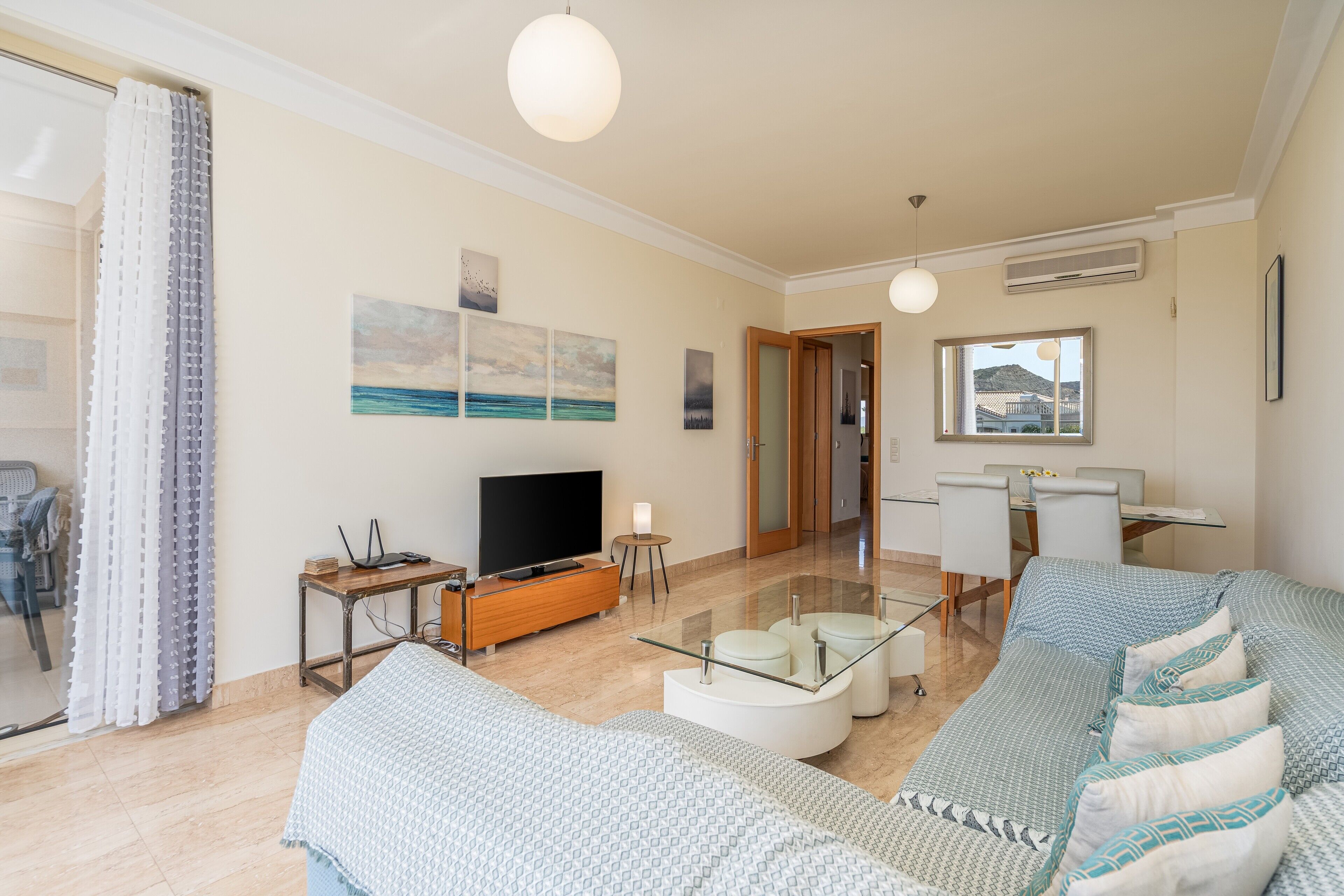 Una sala de estar moderna con sofá, televisor y comedor.