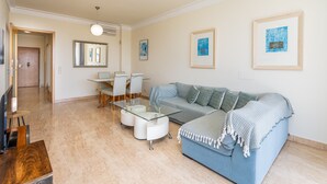 A modern living room with a glass coffee table, a blue sofa, and framed artwork on the walls. - Apartment 'Brightness Comfort In Burgau' with Sea View, Wi-Fi and Air Conditioning (Burgau)