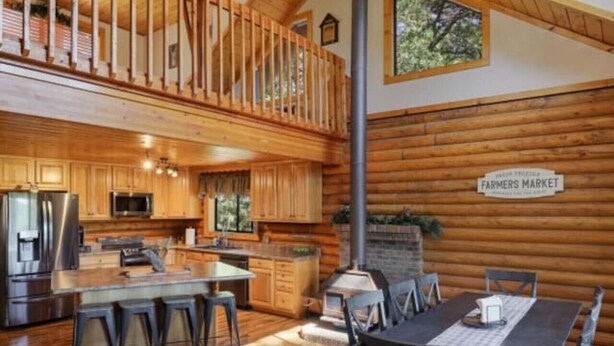 Una cocina amplia con armarios de madera, un refrigerador de acero inoxidable y una isla grande con taburetes de bar.