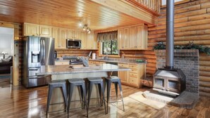 Una cocina amplia con armarios de madera, un refrigerador de acero inoxidable, un microondas y una isla grande con taburetes de bar.