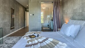 Ein modernes Schlafzimmer mit einem großen Bett, einem Nachttisch und Blick auf einen Balkon.