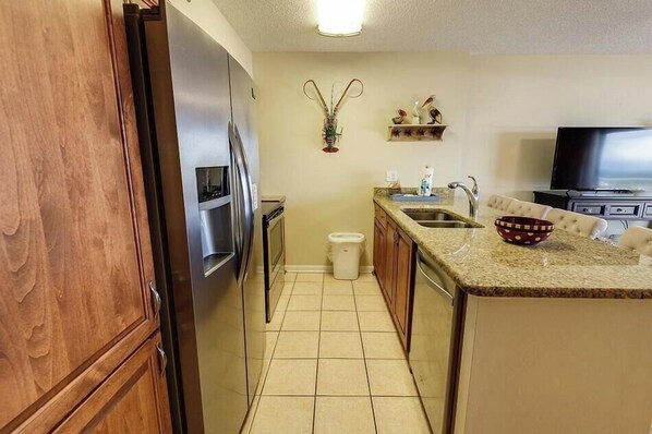 A compact kitchen with a refrigerator, microwave, sink, and a small trash bin.