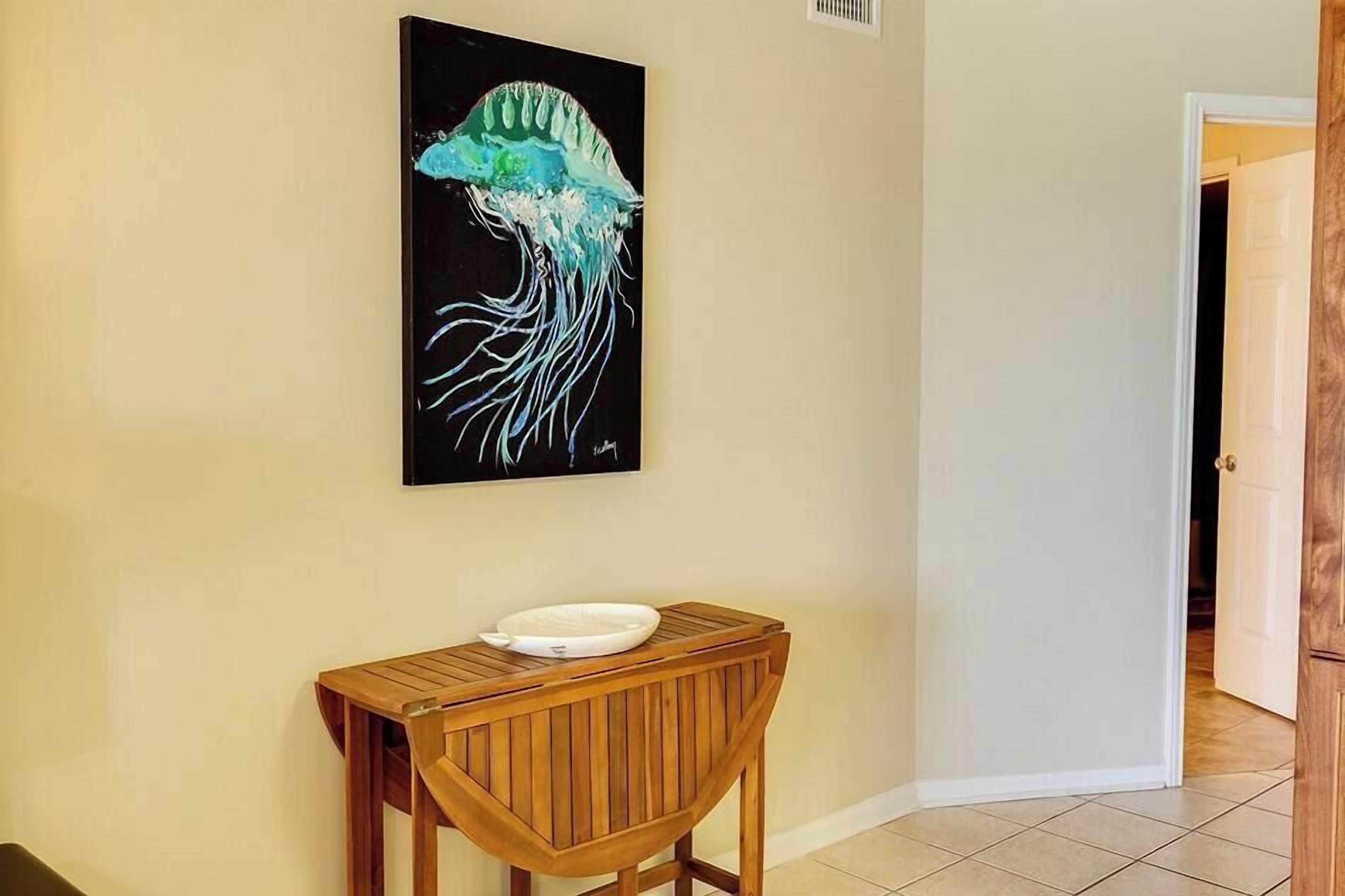 Un pasillo con una consola de madera, un plato blanco y un cuadro de una medusa en la pared.