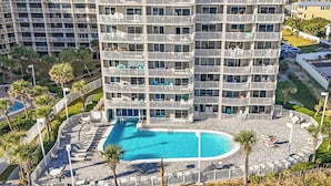 Um hotel moderno com vários sacadões, piscina central e áreas de estar ao ar livre.