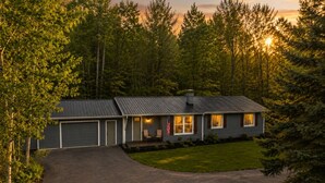 Einbungalow mit Garage, einer Veranda mit zwei Stühlen und einer Flagge.