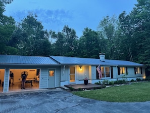 A single-story house with a front porch, a small deck, and a flag. - Modern cottage located near Sister Bay with Game Room and Fire Pit (Ellison Bay)