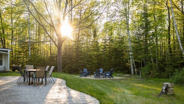 Eine Terrasse mit Tisch und Stühlen, umgeben von Wald.