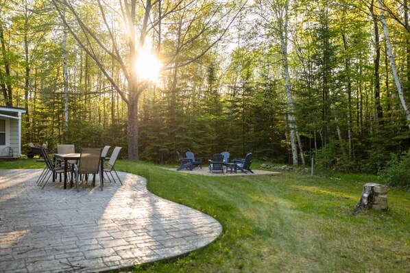 A patio with a table and chairs, surrounded by a wooded area.