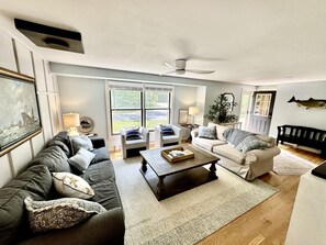 A living room with a sofa, armchairs, a coffee table, and a ceiling fan.