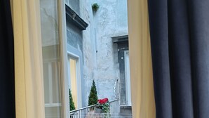 Blick von einem Balkon mit Metallgeländer, einem Blumentopf und einer roten Blume.