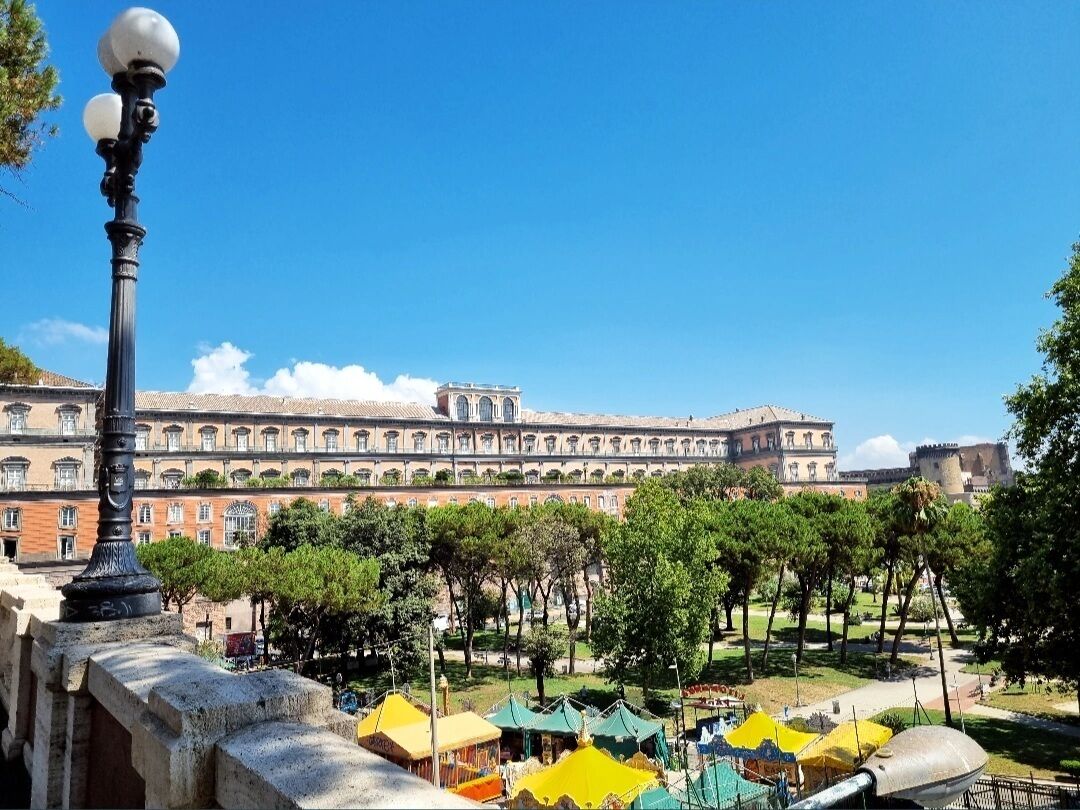 A courtyard with a historic building in the background, a lamp post, and colorful tents.