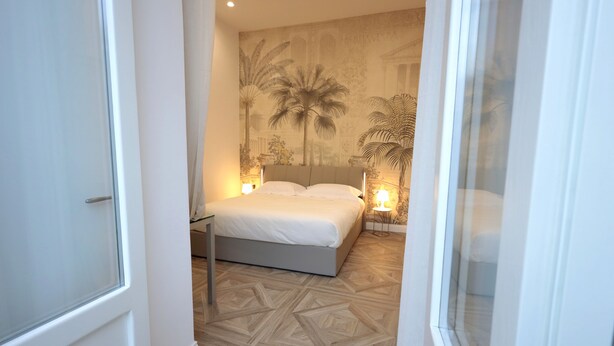 Ein Schlafzimmer mit Bett, Wandgemälde und einem gemusterten Boden.