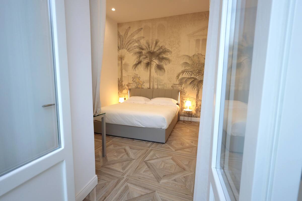 Ein Schlafzimmer mit Bett, Wandgemälde und einem gemusterten Boden.