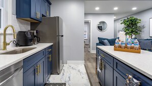 A modern kitchen with dark blue cabinets, stainless steel appliances, and a marble backsplash. - Comfort Meets Style 3-bedroom apartment with Wi-Fi and Parking Close to NYC (New Rochelle)
