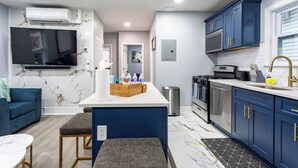A modern kitchen with blue cabinets, a marble backsplash, and a central island. - Comfort Meets Style 3-bedroom apartment with Wi-Fi and Parking Close to NYC (New Rochelle)