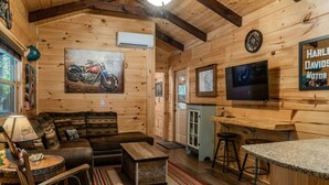 Ein rustikales Blockhaus-Interieur mit Wohnbereich, Bar und Fernseher.