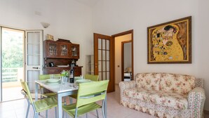Un comedor con una mesa y sillas, un sofá, un armario y un cuadro en la pared.