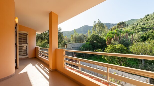 Un balcón con vistas a un paisaje verde y colinas.