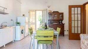Una cocina compacta con lavadora, un comedor con mesa y sillas, y un mueble de madera con puertas de vidrio.