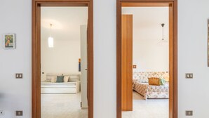 A corridor with wooden doors leading to two rooms, each with a sofa and a lamp. - Arangiu 1 by Interhome (Muravera Villaputzu)
