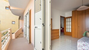 A hallway with open doors leading to a bedroom with a floral bedspread. - Arangiu 1 by Interhome (Muravera Villaputzu)