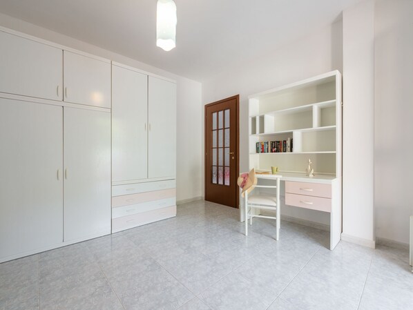 A room with white cabinets, a wooden door, and a desk with books and a hat.