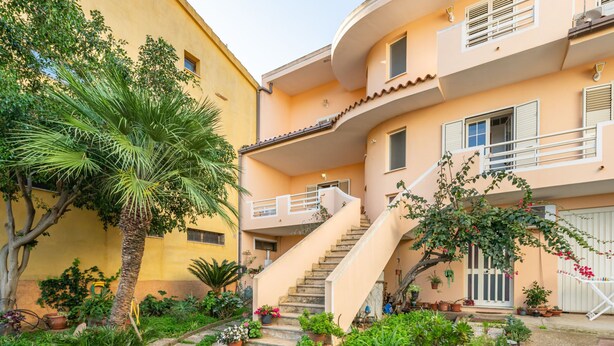 A multi-story building with a curved staircase leading to a balcony. - Arangiu 1 by Interhome (Muravera Villaputzu)