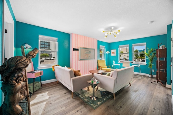 A living room with teal walls, a statue, a sofa, a coffee table, and a chandelier.