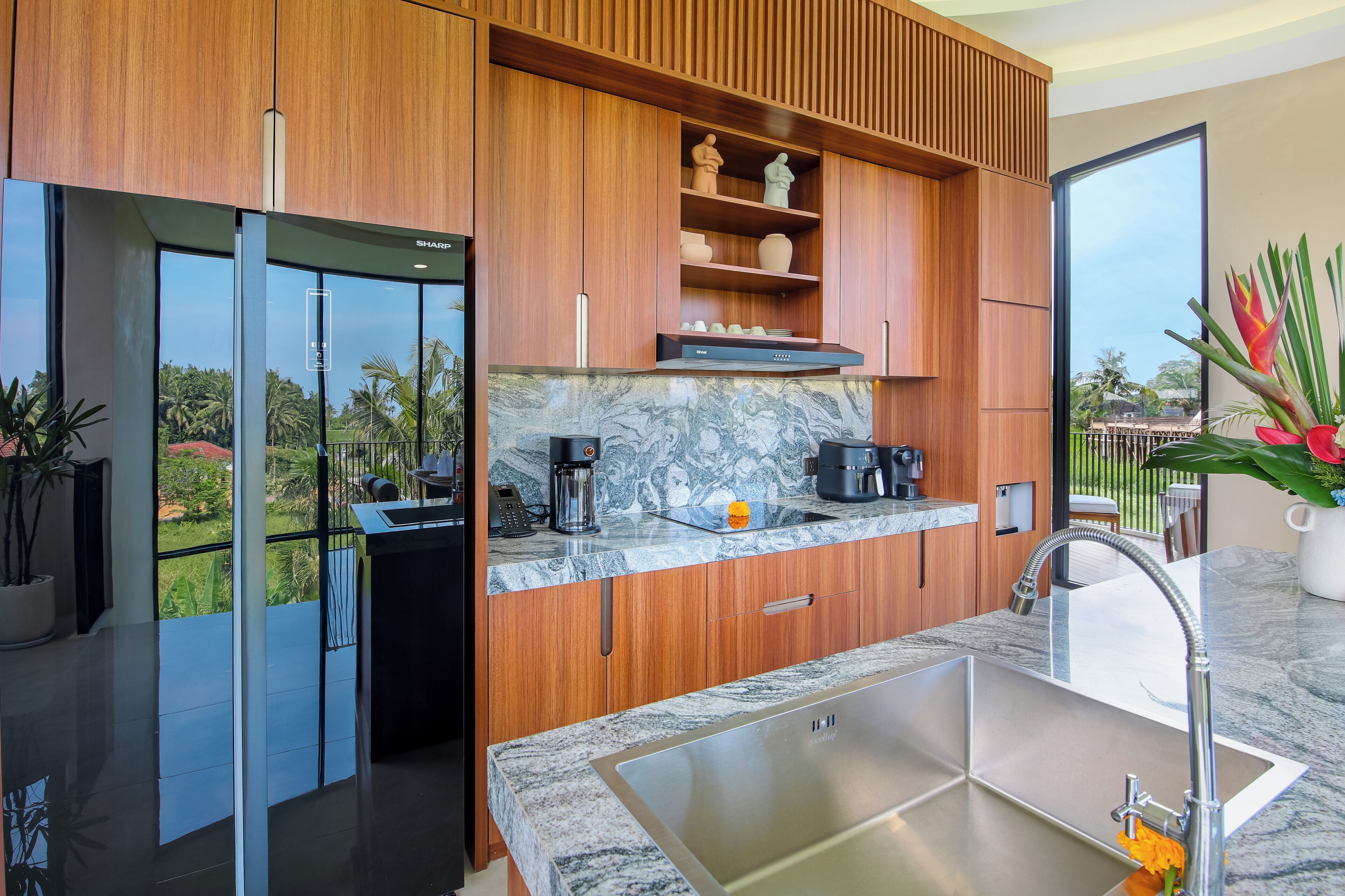 Una cocina moderna con armarios de madera, encimera de mármol y un lavamanos grande.