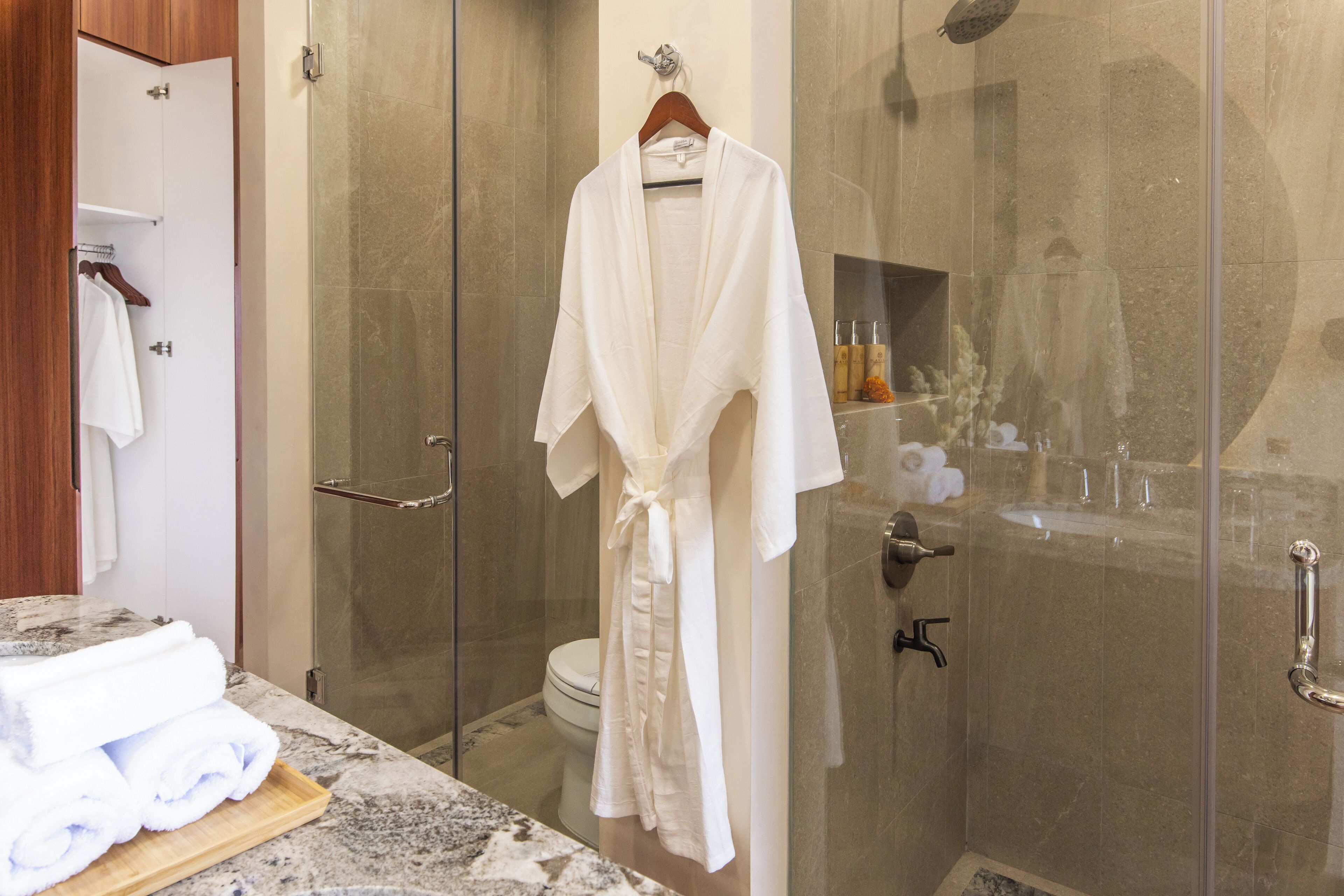 Une salle de bain avec une douche à parois de verre, des toilettes et un lavabo équipé de produits de toilette.