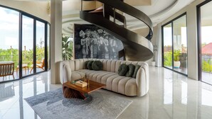 Una sala de estar moderna con una escalera curva, un sofá grande y una mesa de centro.
