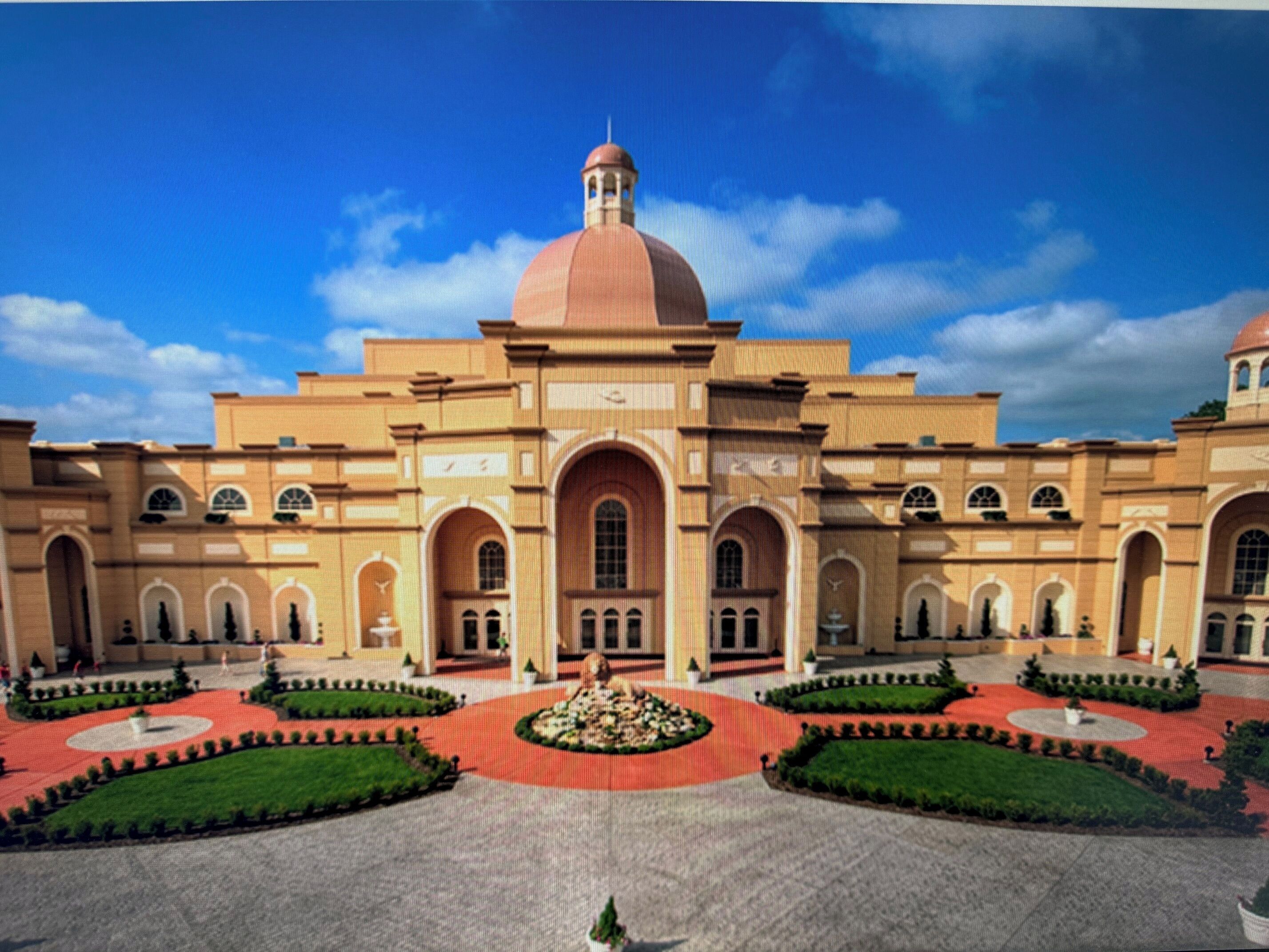 A large building with a central dome, arched windows, and a symmetrical courtyard with a fountain.