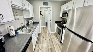A modern kitchen with stainless steel appliances, white cabinets, and a wooden floor.