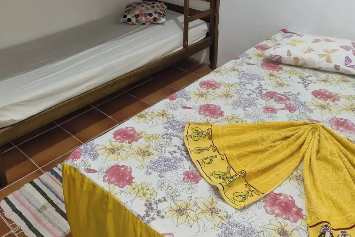 Ein Etagenbett mit zwei Schlafstellen, einer zudeckenden Bettdecke mit Blumenmuster und einem gelben Handtuch auf der unteren Koje.