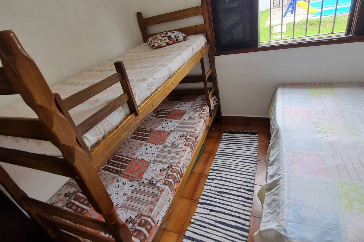 Ein Zimmer mit einem Etagenbett, einem Fenster mit Gitterstäben, einem gemusterten Teppich und einem Bett mit floralem Überwurf.