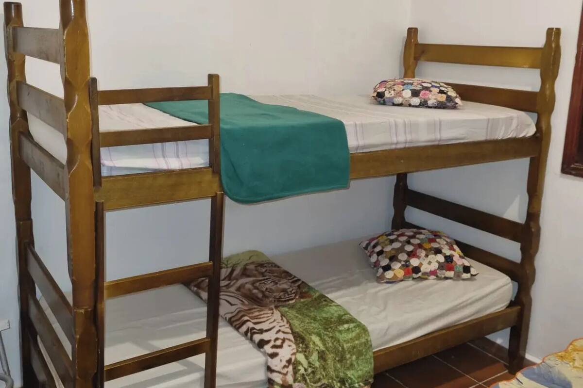 Ein Stockbett mit einer grünen Decke oben und einer gemusterten Decke unten.