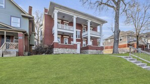 A two-story house with a front porch, a stone foundation, and a well-maintained lawn.