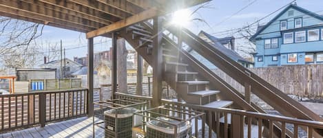 Un espacio al aire libre cubierto con una terraza de madera, una escalera y dos equipos de aire acondicionado.